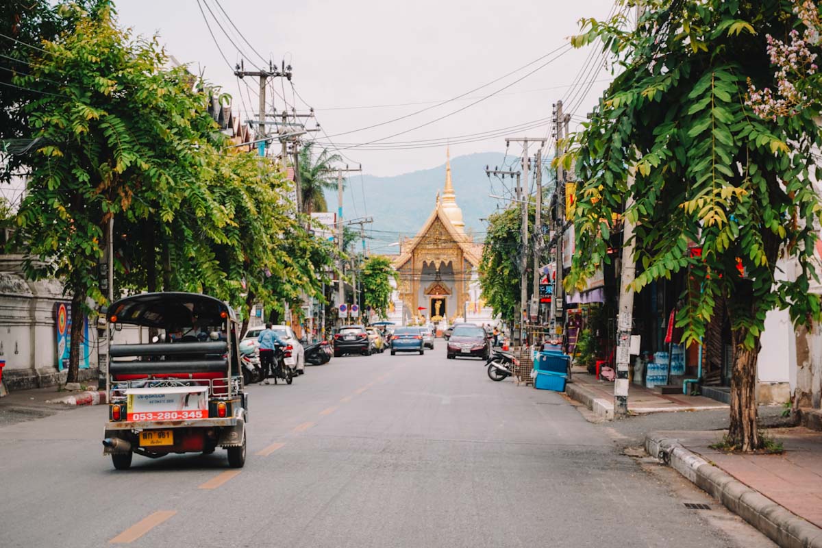 Main street in Chiang Mai with tuktuk and temple