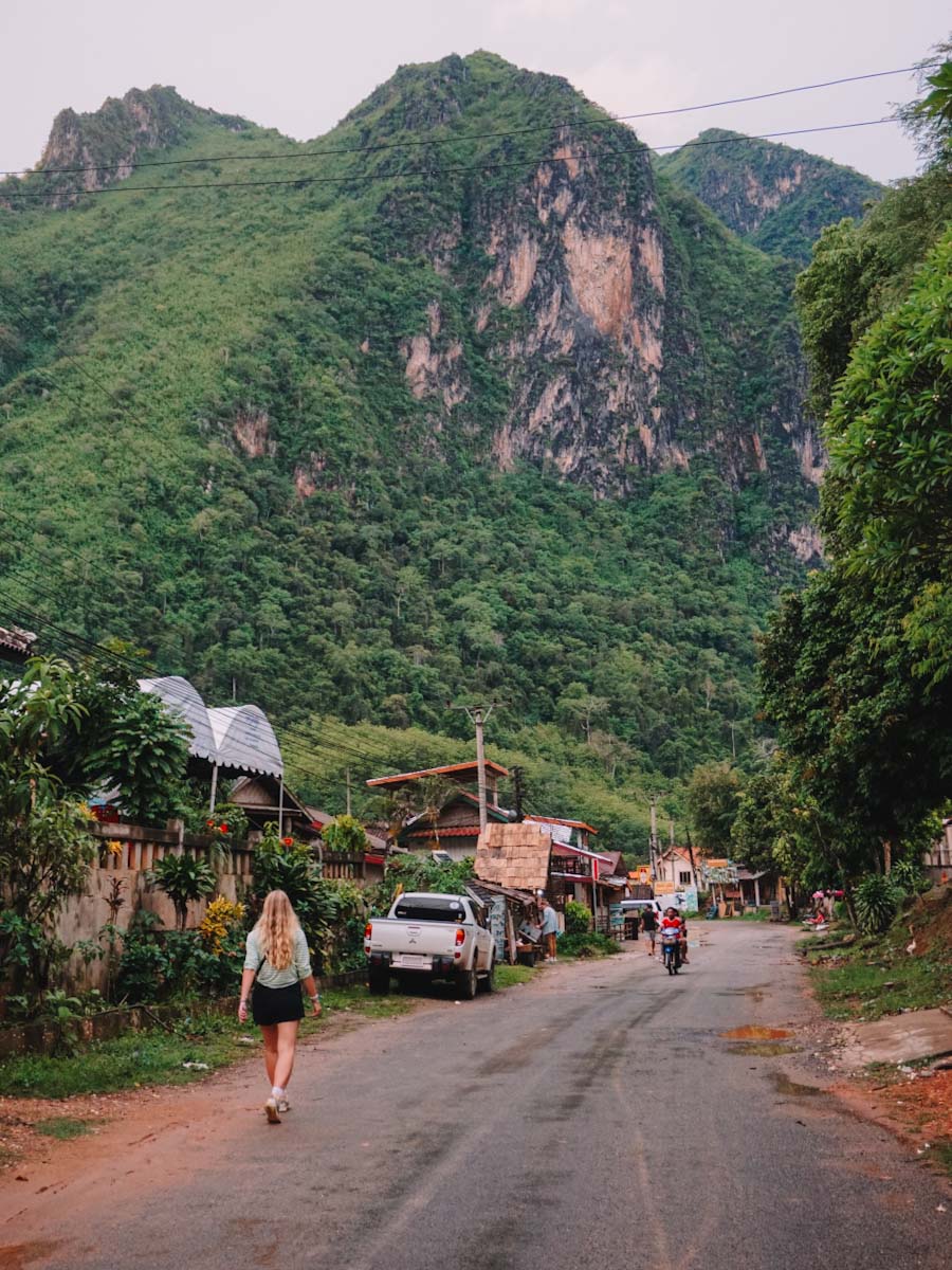 Walking through the main street in Nong Khiaw with mountains in the background