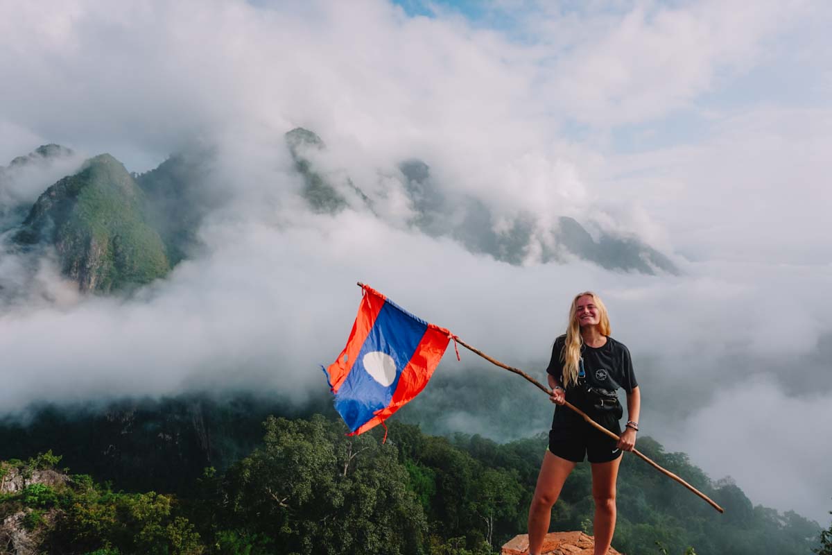 Hiking in Nong Khiaw with mountain in the clouds and Laos flag